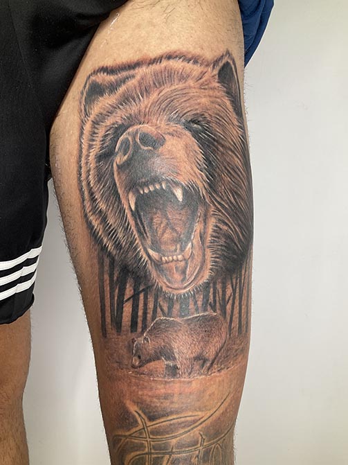 Tatuajes masculinos con significado espiritual de un oso en el muslo