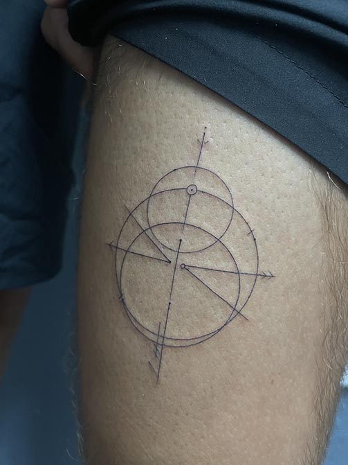 Tatuaje pequeño para hombre de una brújula minimalista en el muslo muslo