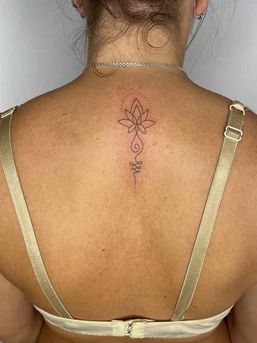 Tatuajes en la columna para mujer de una flor de loto