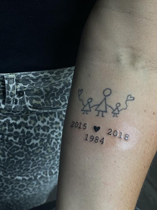Tatuaje de fechas con las años de nacimiento de sus hijos y un corazón para mamás