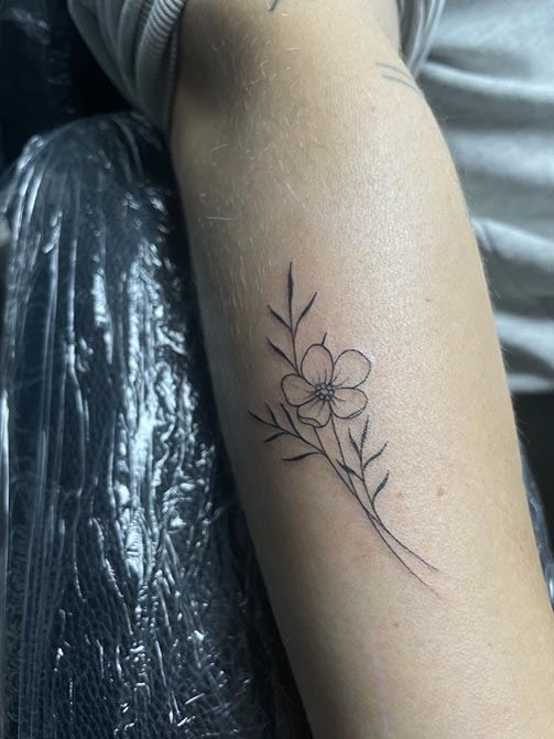 Tatuaje minimalista femenino de una flor de almendro pequeña para mujer en el antebrazo