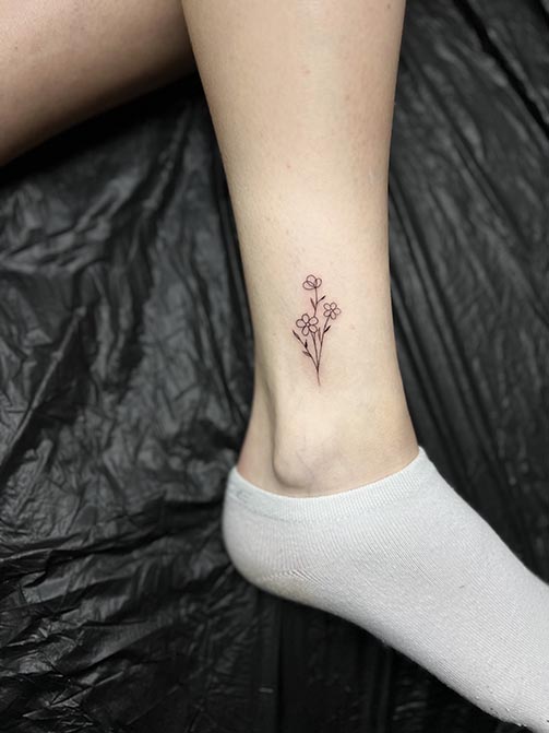 Tatuajes fine line de flores en el tobillo