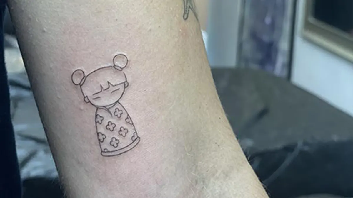 Tatuaje estilo fine line de una muñeca en el brazo