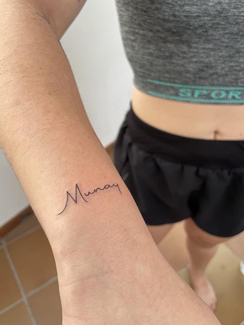 Tatuaje estilo fine line de una palabra en la muñeca