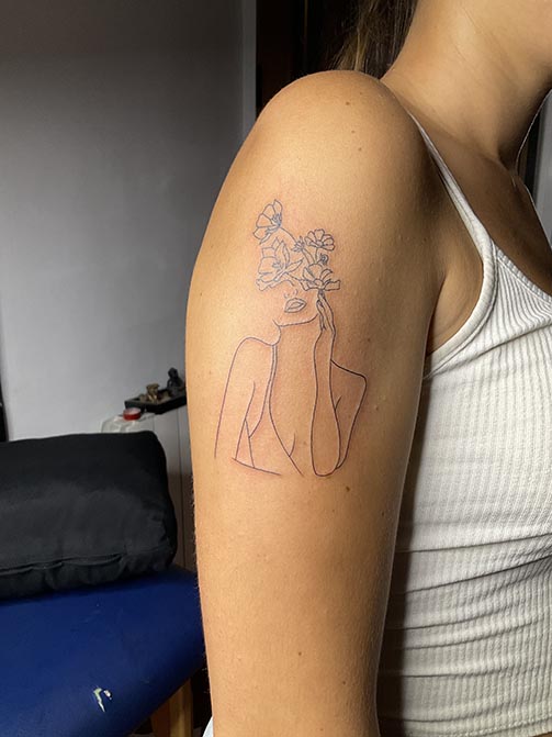 Tatuajes estilo fine line de la silueta de una mujer con flores