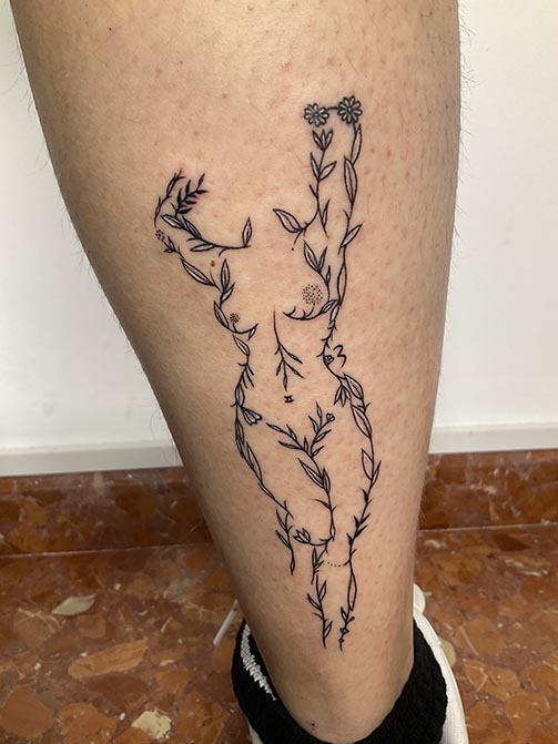 Tatuaje estilo fine line de la silueta del cuerpo de una mujer hecha de ramas y flores