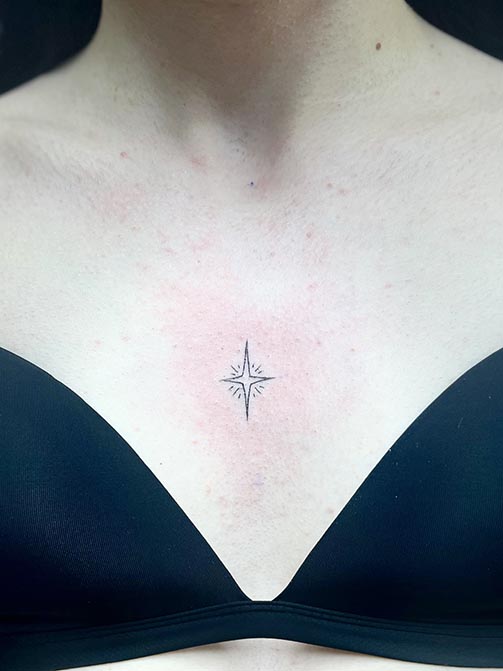 Tatuajes femeninos minimalistas de una estrella pequeña para mujer en el pecho