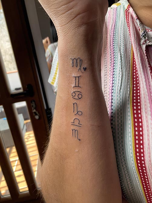 Tatuaje pequeño para mujer en el brazo de símbolos del zodiaco