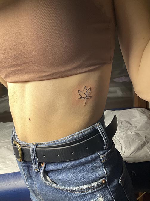 Tatuaje pequeño con significado para mujer  de una flor de loto en las costillas